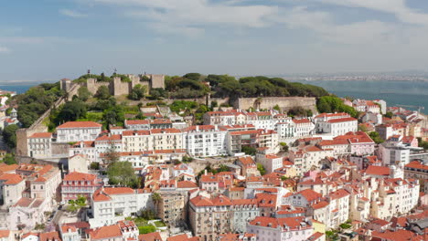 Vista-Aérea-Del-Castillo-De-S-Jorge-Lisboa-En-La-Colina-Sobre-Coloridas-Casas-Tradicionales-En-El-Centro-Urbano-De-Lisboa,-Portugal