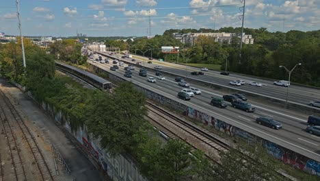 Aerial-view-of-Downtown-Atlanta-city-road-traffic-and-passenger-train-parallel-to-each-other,-Atlanta-traffic,-Georgia,-USA