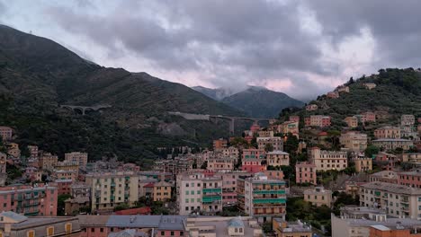 Vista-Nocturna-De-Génova-Nervi,-Italia,-Con-Coloridos-Edificios-Ubicados-En-Exuberantes-Colinas-Verdes.