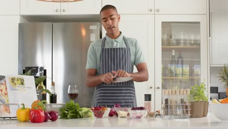 vlogger de cocina masculino biracial en delantal hablando y filmando en la cocina