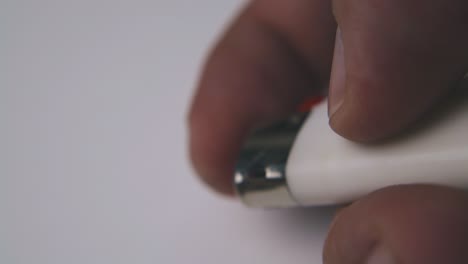 man burns plastic lighter by finger on white background