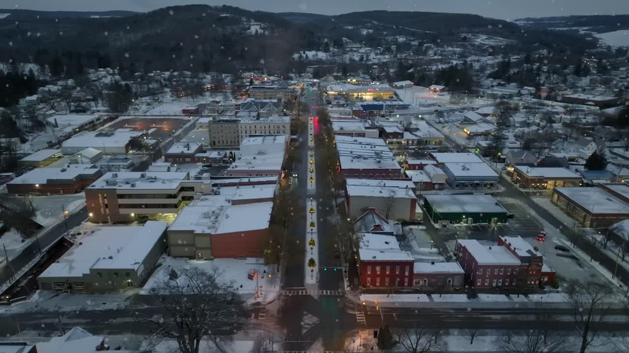 Ripresa aerea orbitante di fiocchi di neve che cadono su una piccola città in America