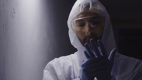 Man-in-protective-suit-preparing-gloves,-nuclear-disaster-concept,-face-middle-shot
