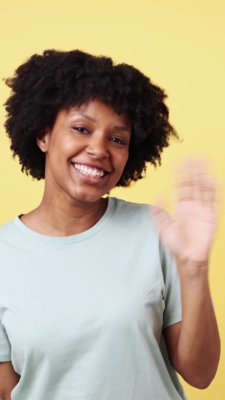 Cheerful Black Woman Waving and Smiling on Yellow Background