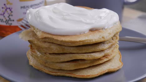 topping a tall stack pf pancakes with fresh yogurt