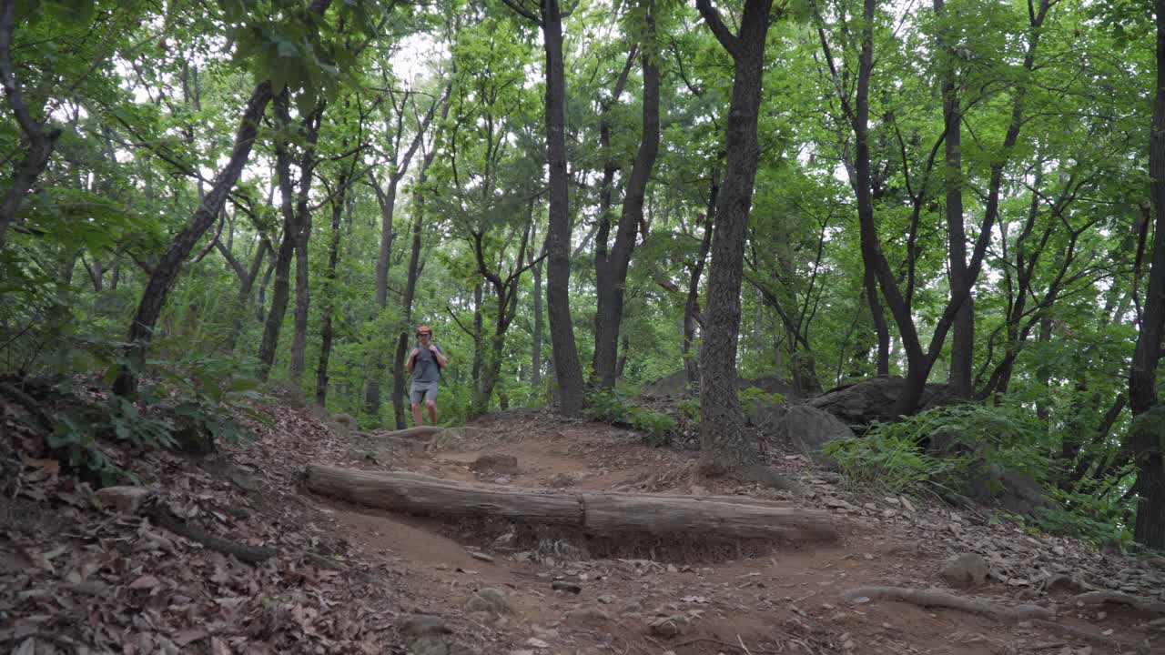 European tourist hiker walks down the trail path sweat and tired, forest frees background low angle view