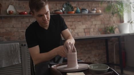 man shaping clay on pottery wheel