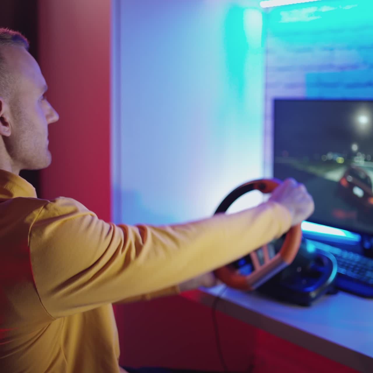 Giovane gamer che guida il volante di un simulatore di corse. Uomo felice che si diverte con un videogioco di corse automobilistiche con un volante. Simulazione al computer