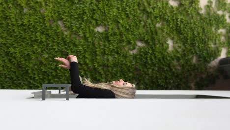 beautiful woman getting fresh air from window terrace with floral wall, vertical