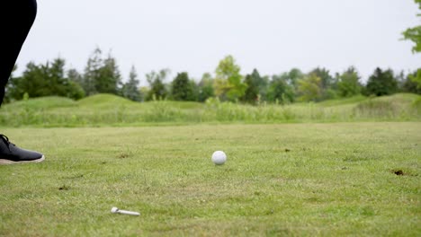 slow motion shot of a golfer hitting a golf ball of a tee with an iron