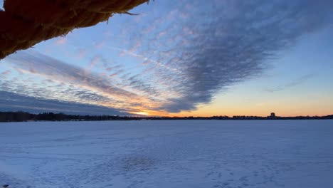 clouds rolling over a frozen lake in minnesota after sunset, time lapse