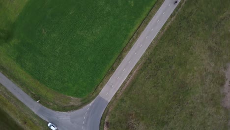 Toma-Aérea-De-Un-Motociclista-Conduciendo-Por-Una-Pequeña-Carretera-Agrícola