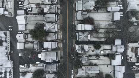 top down aerial view of white roofs of houses and homes in small town america during beautiful heavy snowstorm in dead of winter