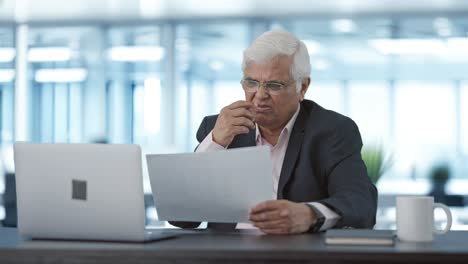 confused indian senior manager reading business reports