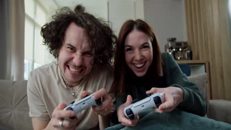 Portrait-of-a-brunette-guy-with-straight-hair-and-a-mustache-having-fun-with-his-brunette-girlfriend-and-playing-video-games-with-a-joystick-at-home-on-the-couch