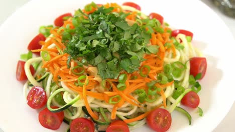 Top-view-shot-of-zucchini-spiralizer-on-lazy-susan-shredded-carrots-sliced-tomatoes