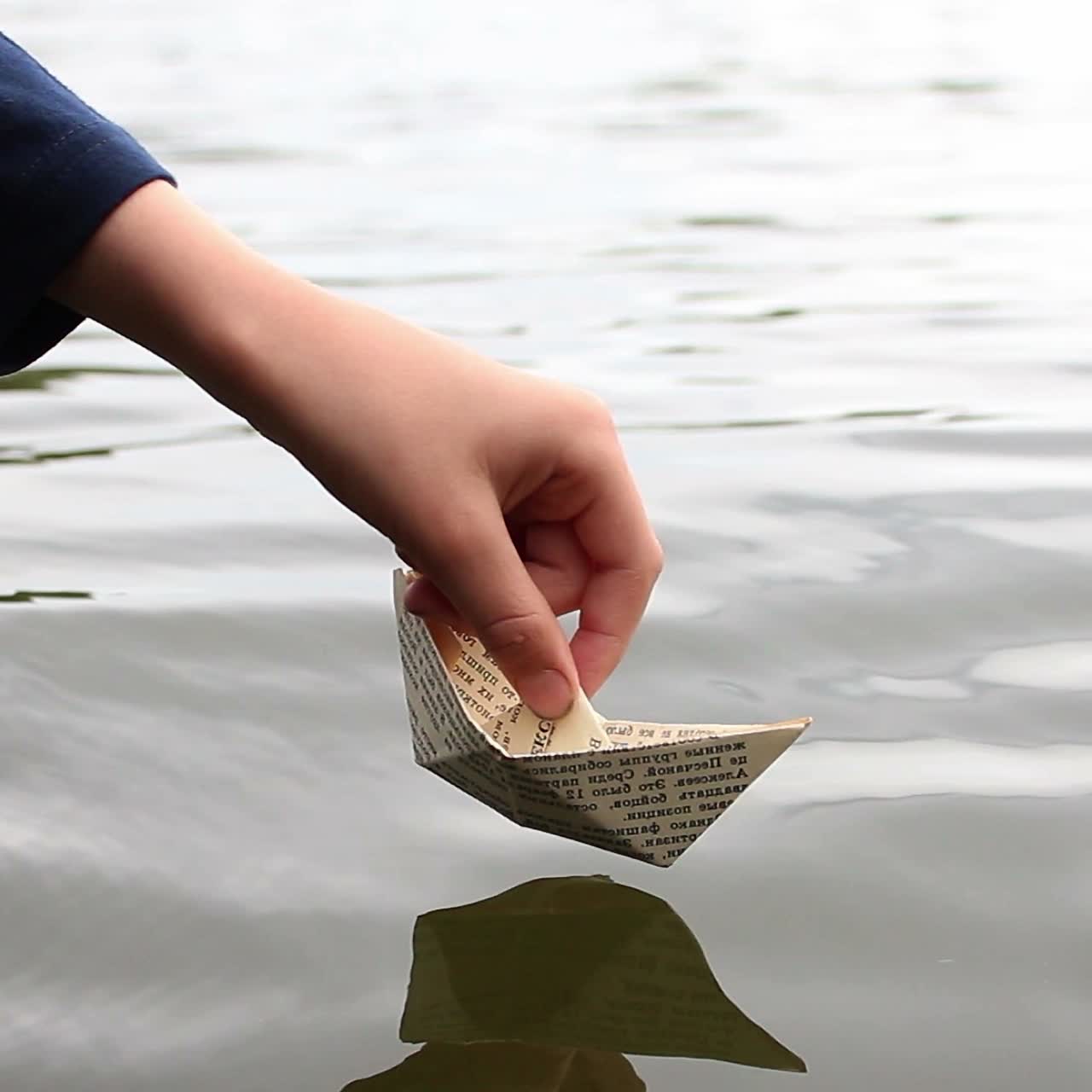 The Boy Playing Near Water. The boy playing launches a paper boat