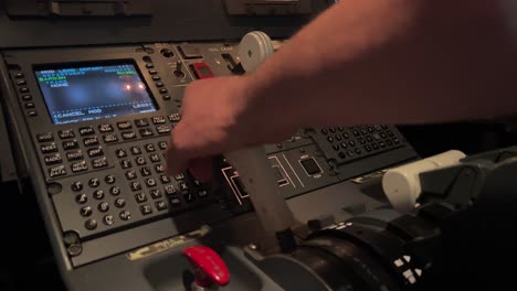 captain handling the fms computer inside a real jet cockpit during the pre-flight checks