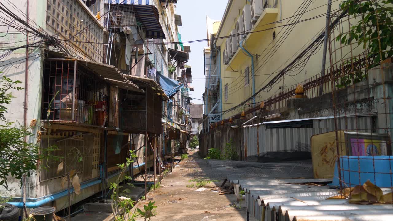 Narrow alley in Bangkok city, where lower-class residents live among old buildings and cluttered surroundings