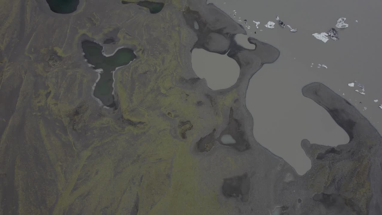 vista aérea de arena oscura y musgo, en la laguna del glaciar solheimajokull, en islandia - aumento, disparo de drones
