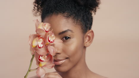 beauty portrait beautiful african american woman playfully posing with orchid flower touching healthy skin complexion enjoying gentle fragrance of natural essence skincare concept