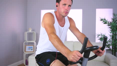 handsome sporty man training on exercise bike and listening to music