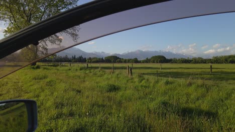 tierras de cultivo y montañas nevadas vistas a través de la ventana abierta del camión durante la puesta de sol
