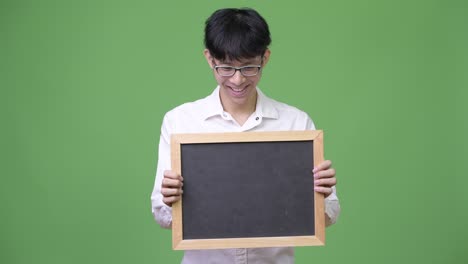 young asian businessman holding while looking at blackboard