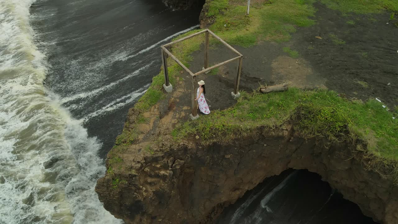 절벽 위의 나무 입방체 위를 걷는 여성의 궤도