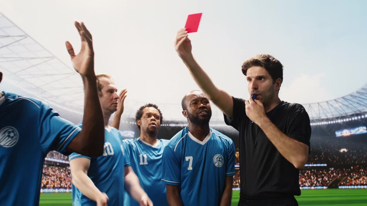 Cartellino rosso mostrato dall'arbitro di calcio con i giocatori che protestano contro la decisione di espulsione