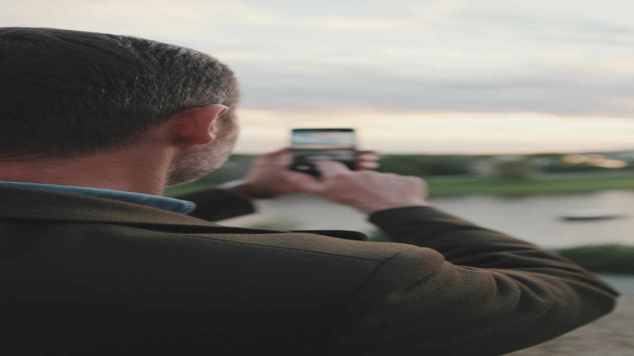 Man taking a photo of the city at sunset