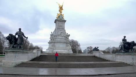 Wide-shot-of-single-person-walking-towards-the-Victoria-Memorial-with-no-tourists-around,-London