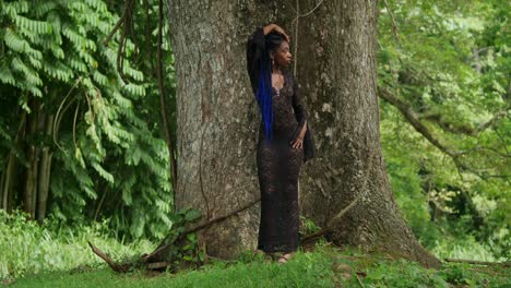 beautiful woman in black lace dress posing in lush tropical forest