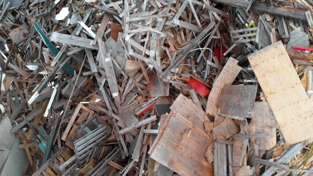 Ripresa aerea a bassa quota ravvicinata su un'enorme discarica piena di tonnellate di rifiuti legnosi e ingombranti.