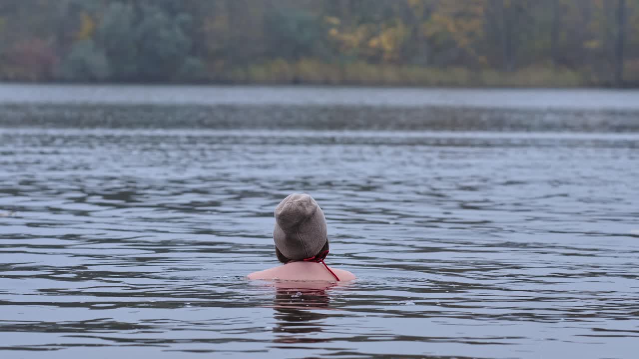 A woman enjoying a refreshing cold water, embracing nature's beauty in autumn