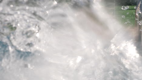 a boy in an open pool happily spattering the water