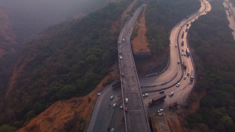 multi lane pune mumbai expressway traffic in evening, carved through mountain valley, lonavala, maharashtra, drone shot