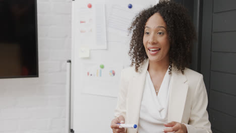 Glückliche-Biracial-Geschäftsfrau-Am-Whiteboard,-Die-Bei-Einer-Bürobesprechung-In-Zeitlupe-Spricht