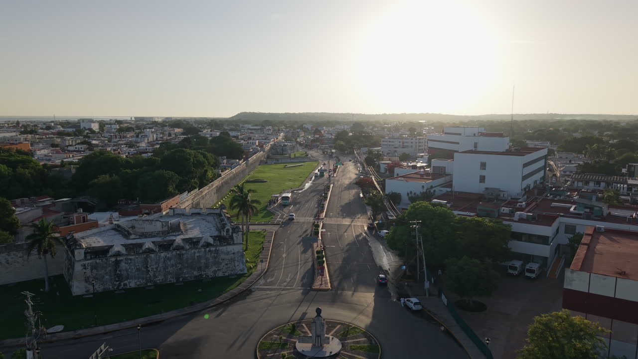 Aerial drone shot flying toward sunrise with scenic view of San Juan Bastion and Campeche city walls in Mexico