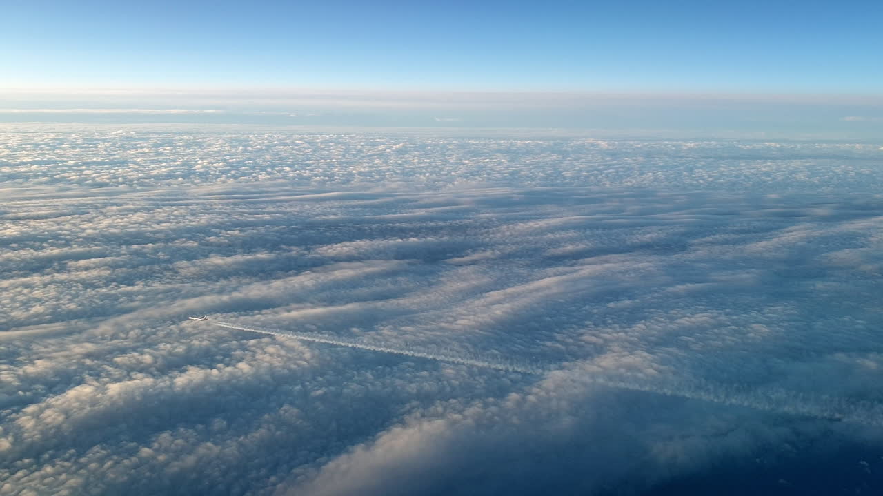 vista increíble desde la cabina de un avión que vuela alto por encima de las nubes dejando un largo rastro de aire de vapor de condensación blanco en el cielo azul