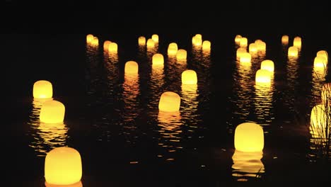 Linternas-Flotantes-Japonesas-En-La-Noche,-Iluminando-Ondas-En-El-Agua