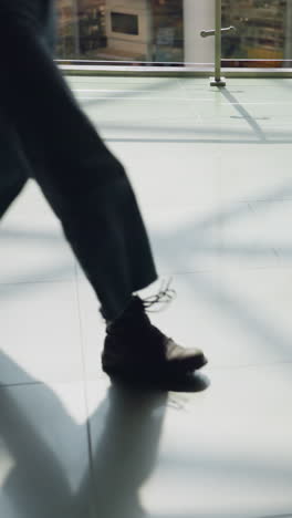 una vista de un piso de azulejos de un centro comercial con los pies de la gente moviéndose, incluida una persona con vaqueros y botas negras caminando. este video hace hincapié en el movimiento y la dinámica de un bullicioso entorno comercial