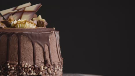 close up studio shot of freshly baked and decorated chocolate celebration cake revolving against black background 1