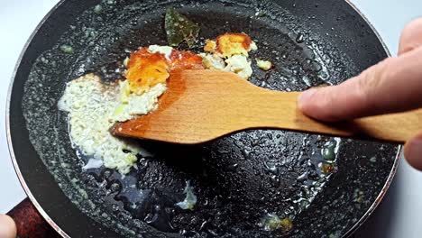 dirty pan in oil. unhealthy food. damaged kitchenware. man scrapes off leftover food.
