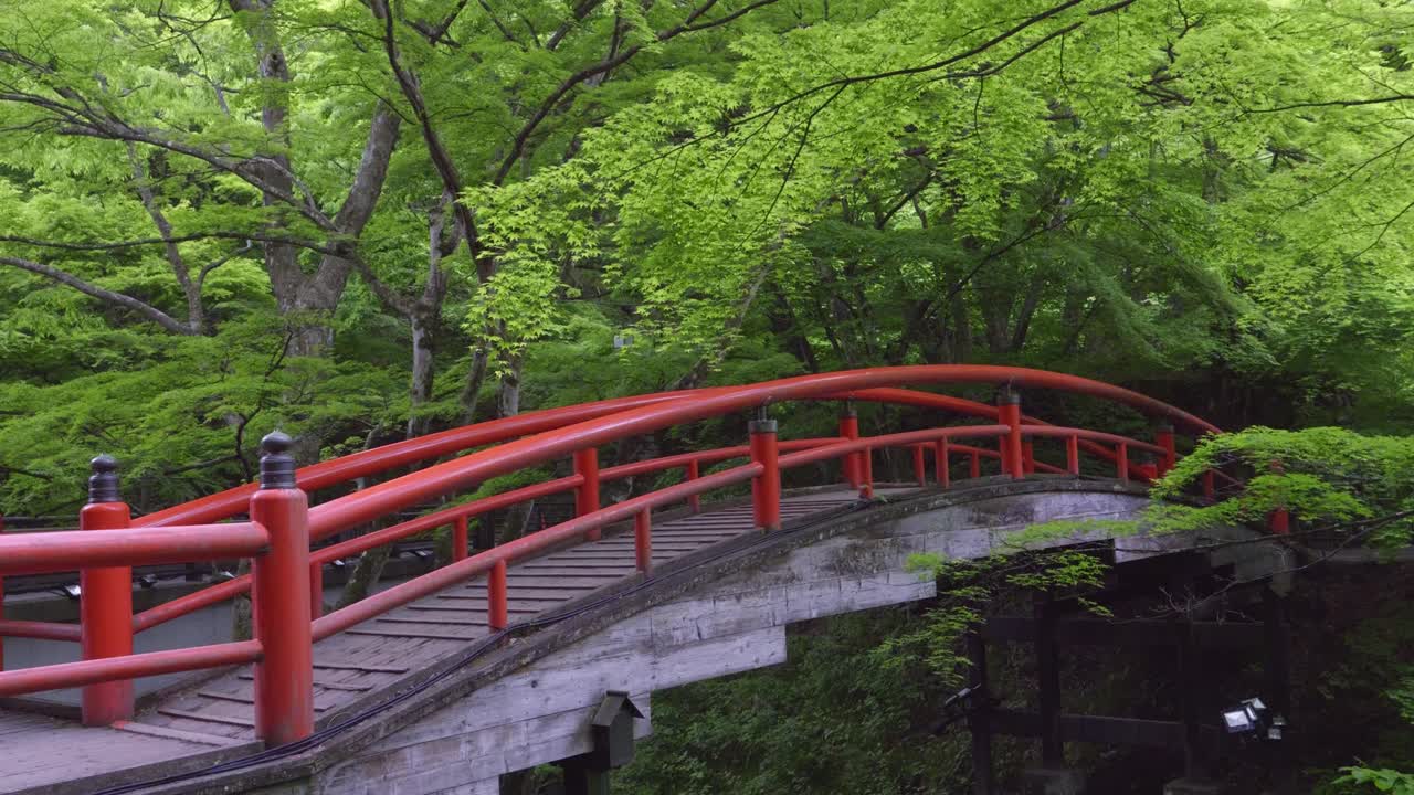 Slow sideways slider over Kaijka bridge inside lush green forest near Ikaho Onsen