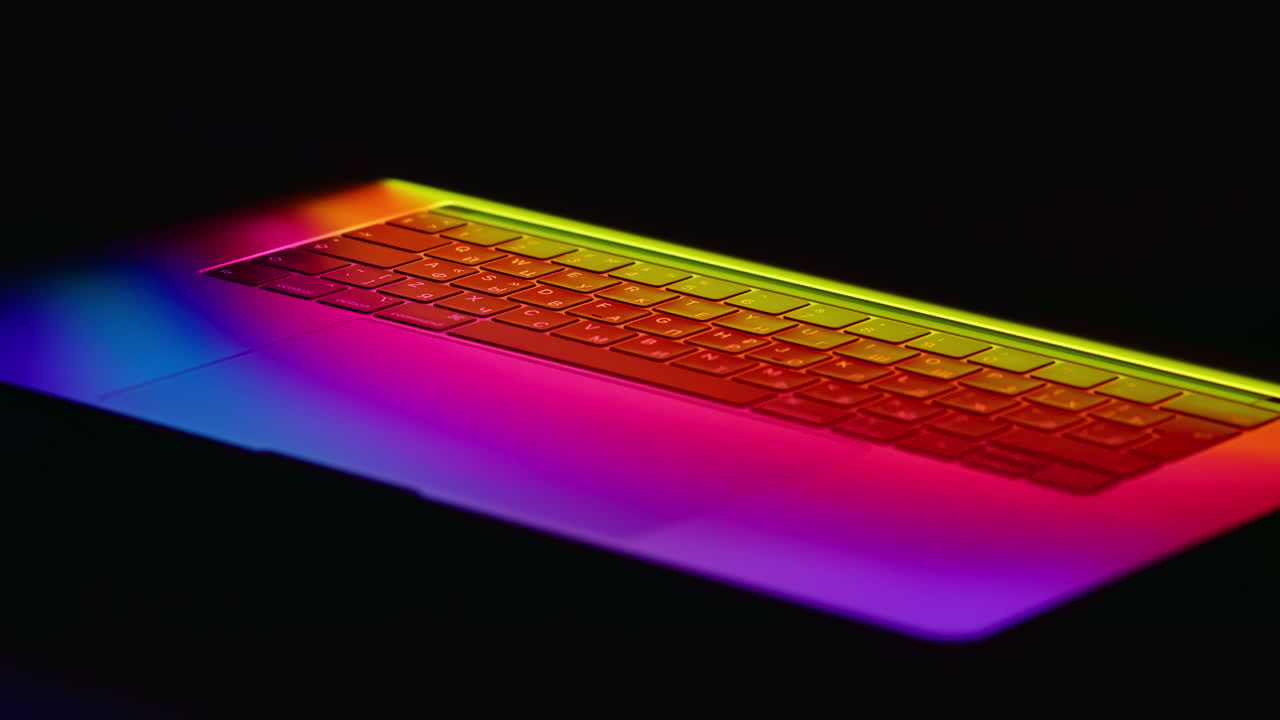 rack se centra en un teclado de portátil moderno iluminado en un resplandor de neón arco iris