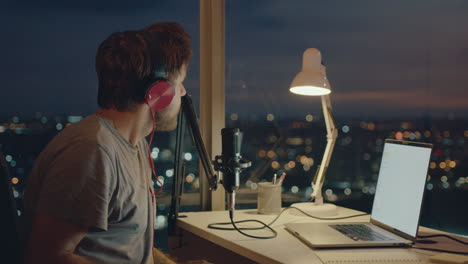 a bearded man is streaming against the background of a panoramic window at dusk