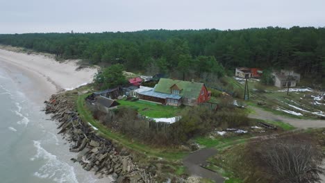 aerial establishing view of baltic sea coast on a overcast winter day, a house at the beach with white sand, coastal erosion, climate changes, wide orbiting drone shot