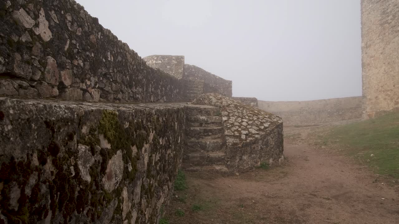 Panoramica sui gradini muschiosi in una mattina nebbiosa al Castello di Marvão