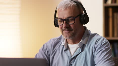 man working on laptop with headphones and glasses